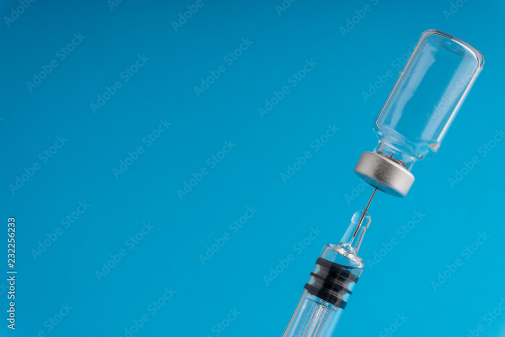 Medical syringe and vial on blue background with selective focus and crop fragment Medical syringe and vial on blue background with selective focus and crop fragment