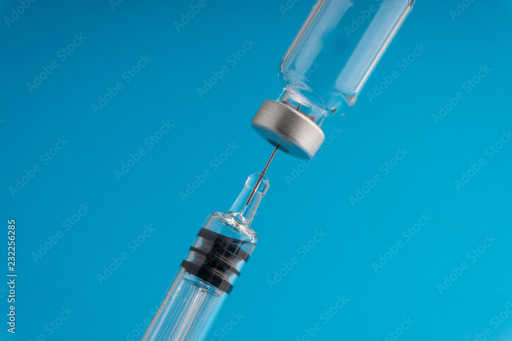 Medical syringe and vial on blue background with selective focus and crop fragment Medical syringe and vial on blue background with selective focus and crop fragment