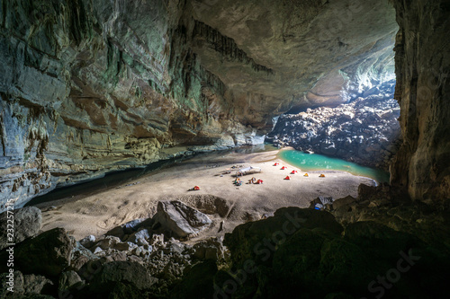 Hang En Cave - Tourists Camp Inside Large Cave in Vietnam. Cave with a beach, water lagoon and tents inside.