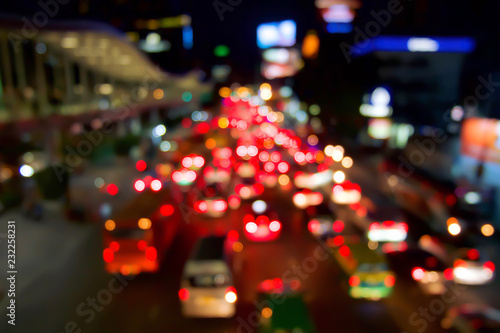 Red bokeh light from car on road in the city at night time at Rajdamri Road, Bangkok, Thailand. Defocused of night traffic. Abstract or blurred of light glitter. Glow texture background.
