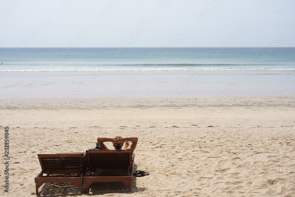 A man is relaxing on a chair on the beach A man is relaxing on a chair on the beach