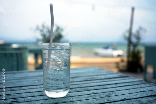 glass of water with straw on table in cafe near beach