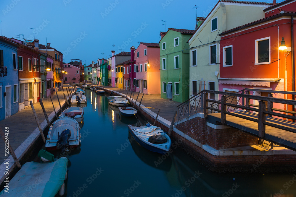 Old colorful houses and boats at night in Burano,  Italy.