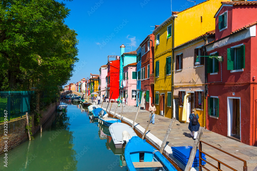 ITALY, BURANO - SEPTEMBER 26, 2017: Colourful houses along the canal on the island of Burano.The island is a popular attraction for tourists due to its picturesque architecture