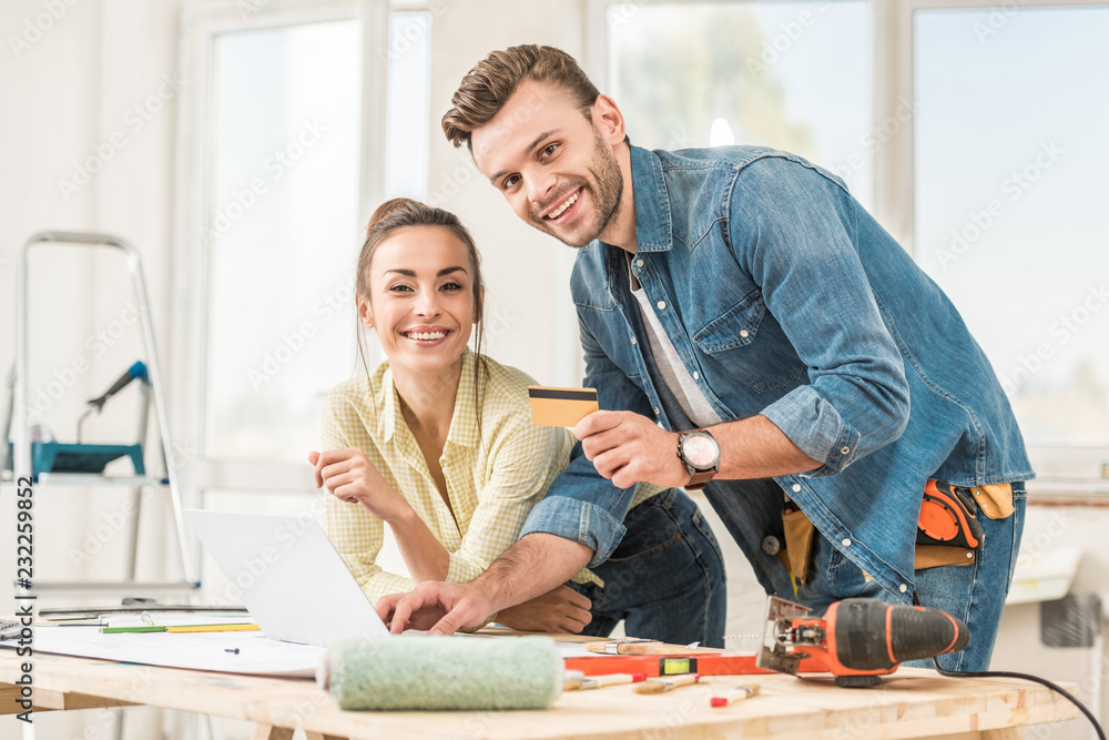 happy young couple with credit card smiling at camera during home improvement happy young couple with credit card smiling at camera during home improvement
