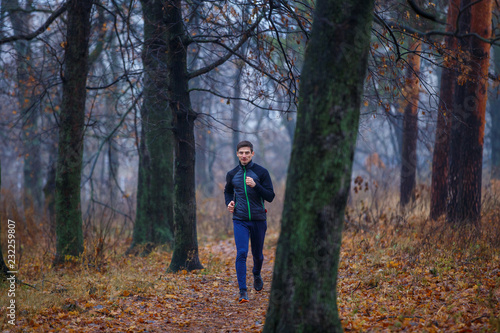 Young man jogging in autumn park in the morning