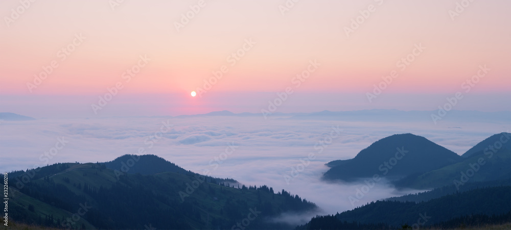 Pink dawn above the clouds in the mountains