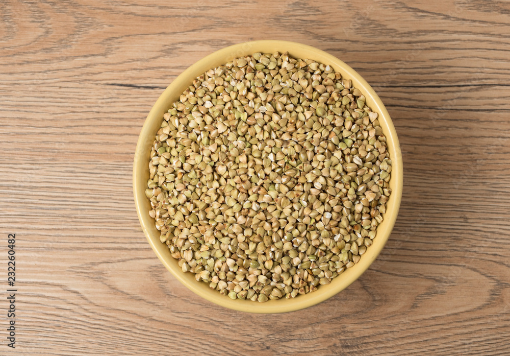 Natural fresh green buckwheat in ceramic bowl on wooden background. Natural fresh green buckwheat in ceramic bowl on wooden background.