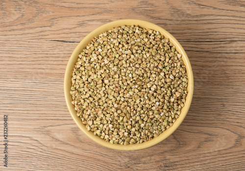 Natural fresh green buckwheat in ceramic bowl on wooden background.