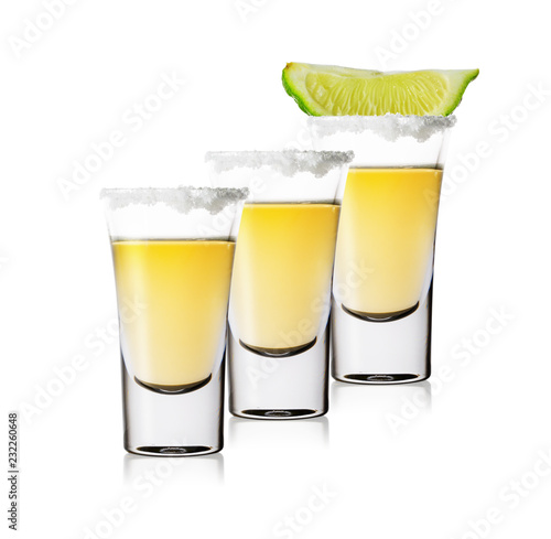 Three glasses of golden tequila standing in row