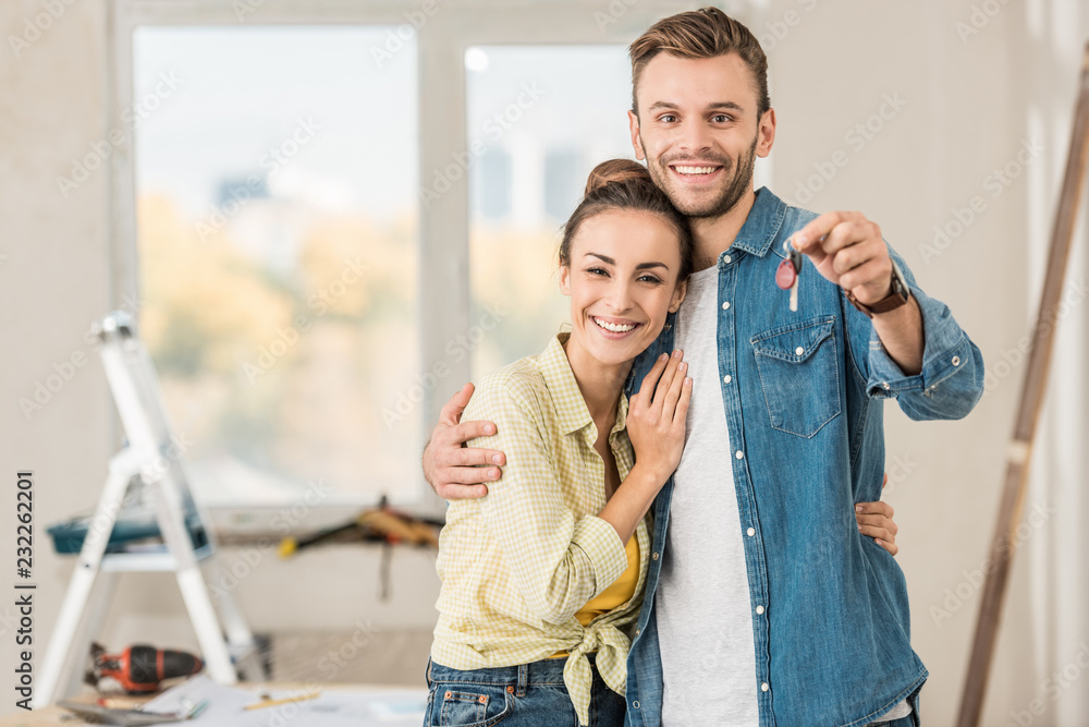 happy young couple holding key from new apartment and smiling at camera happy young couple holding key from new apartment and smiling at camera