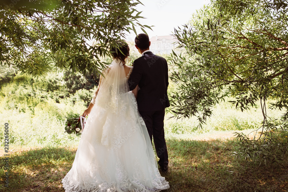 Newlyweds walking together in nature, romantic landscapes for two during a wedding photo shoot