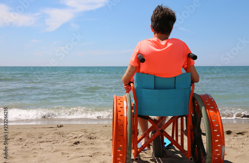 boy on the special wheelchair with metal wheels on the beach photo