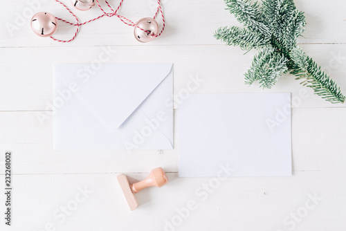 Christmas composition with card mockup. Christmas decor, balls, wyite envelopes, stamp, fir branches on wooden white background. Flat lay, top view, copy space photo