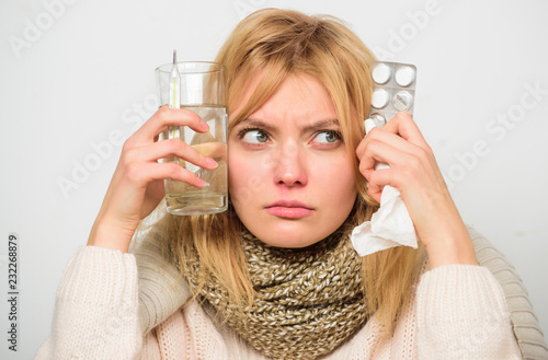 Getting fast relief. Ways to feel better fast. Flu home remedies. Woman wear warm scarf because illness or flu. Girl hold glass water tablets and thermometer light background close up. Get rid of flu