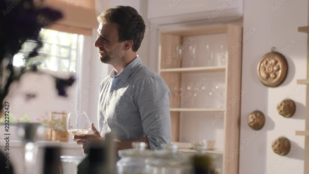 Young man drinks wine from the glass, smiles and chats to somebody on the home party at the sunny summer day, tasting of wines, home party Young man drinks wine from the glass, smiles and chats to somebody on the home party at the sunny summer day, tasting of wines, home party