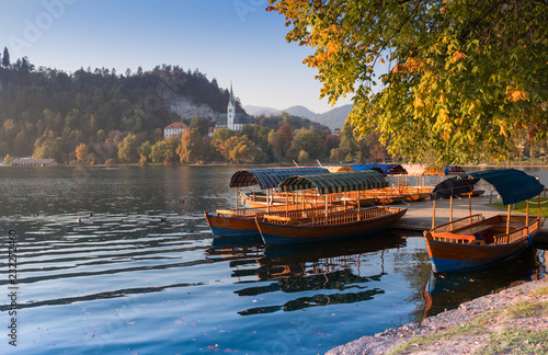 Traditional pletna boats on the  waters of Lake Bled with Bled Castle cliff on the background, Upper Carniola, Slovenia. Colorful autumn