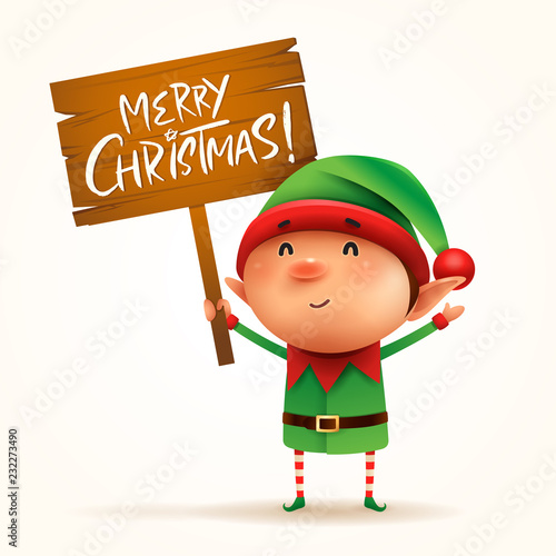 Little elf holds a wooden board with Christmas greetings. Isolated.