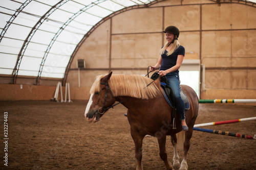 Young adult beautiful woman in helmet learning Horseback Riding