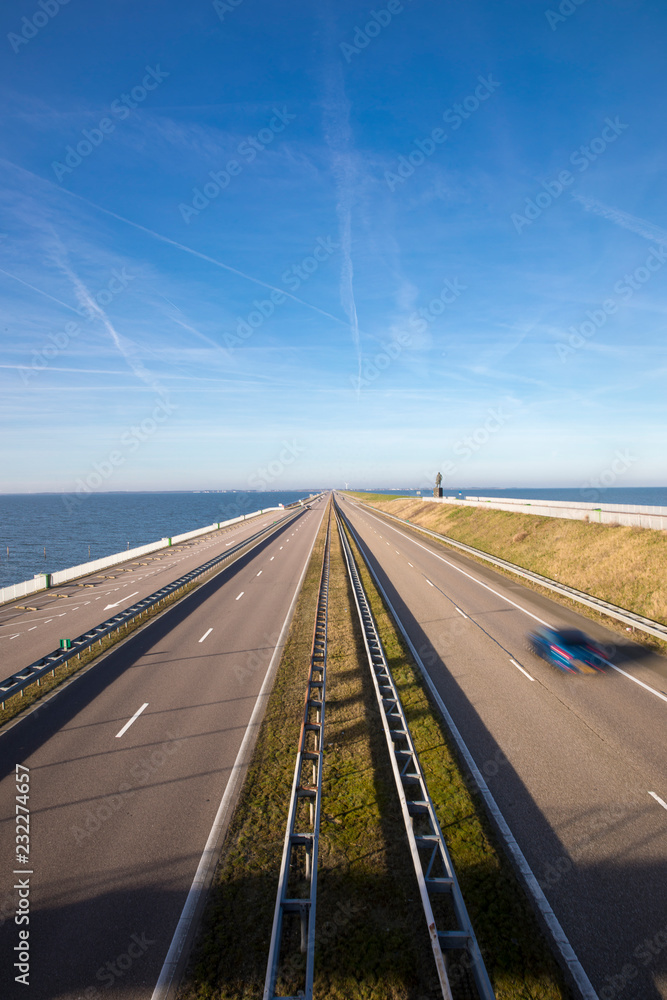Motorway A7 on Afsluitdijk, a dam separating the North Sea from the Ijsselmeer lake. View from bridge at Breezanddijk, an artificial island.