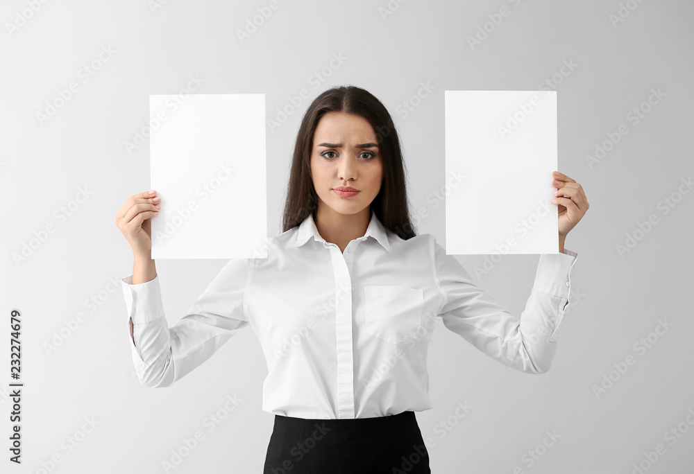 Emotional young woman with blank sheets of paper on light background Emotional young woman with blank sheets of paper on light background