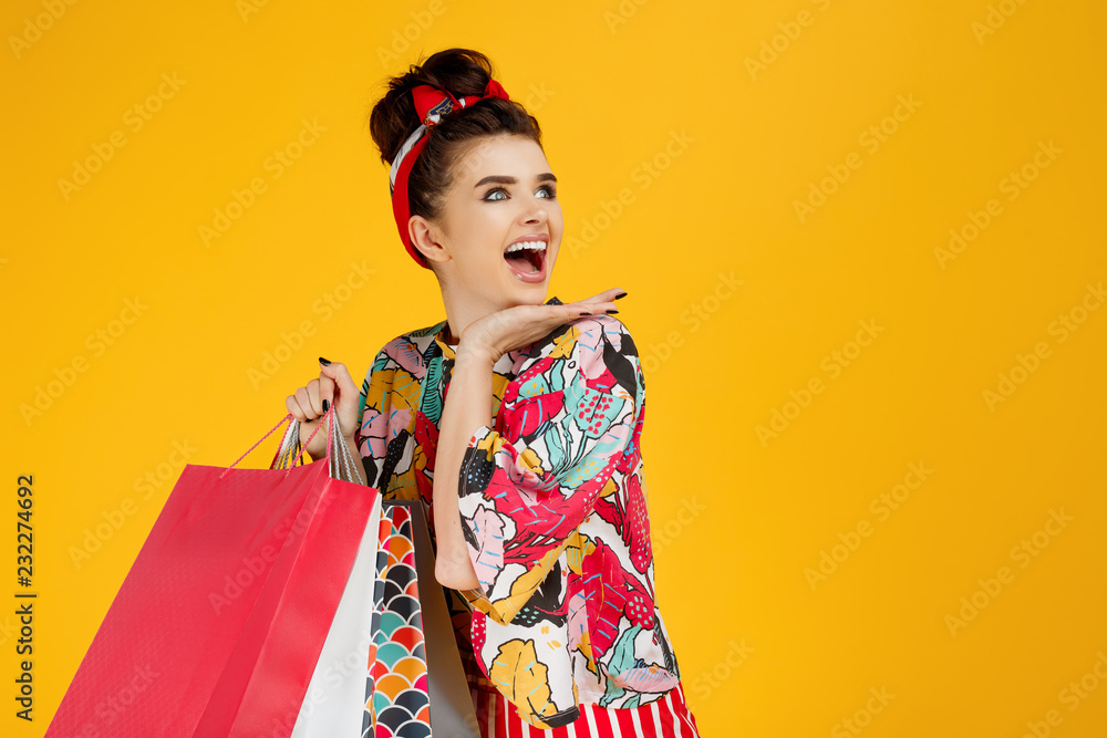 Young happy caucasian woman in casual colorful clothes holding bags and shopping over orange background. Young happy caucasian woman in casual colorful clothes holding bags and shopping over orange background.