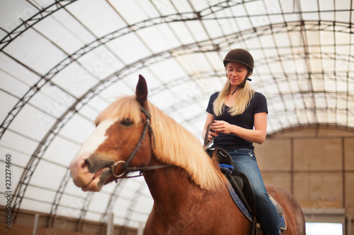 Young adult beautiful woman in helmet learning Horseback Riding