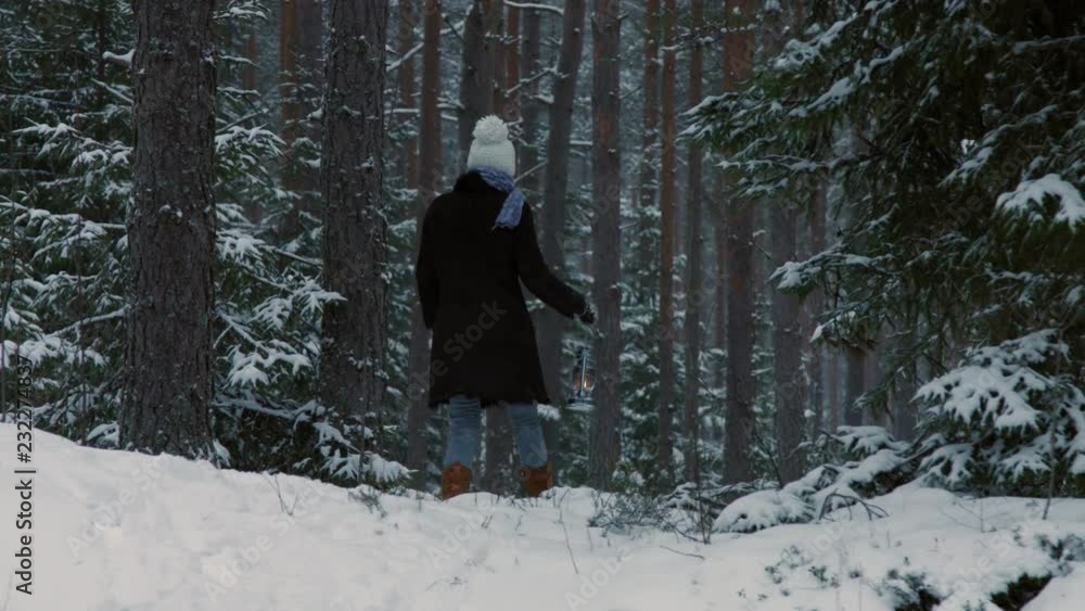 Woman with old lantern walking in snow covered wild forest in winter Woman with old lantern walking in snow covered wild forest in winter