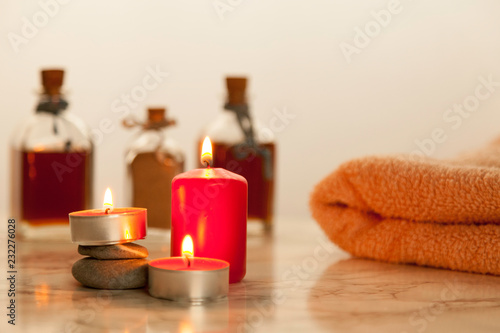 burning red candles  and bath oils on marble