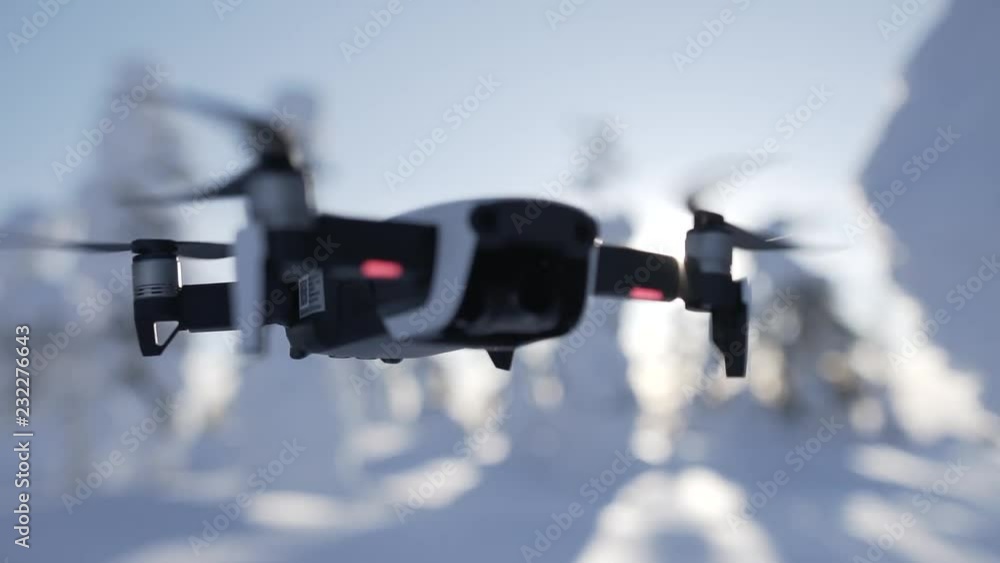Close-up shot of a small white drone hovering in winter while changing focus, slow motion Close-up shot of a small white drone hovering in winter while changing focus, slow motion