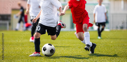 Two Young Boys in Soccer Sportswear Running and Kicking Ball on the Field. Low Angle Image of Youth Football Competition with Blurred Background © matimix