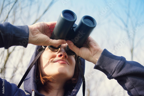 Girl with the field-glass watches birds. Ornithology. Birdwatching