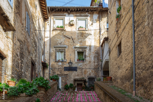 Fototapeta Naklejka Na Ścianę i Meble -  Small courtyard with a cat on the windowsill in the historic town of Spoleto. Italy