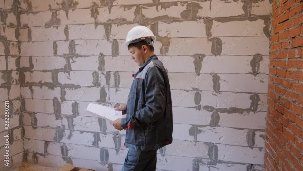 Man with papers exploring room in building under construction Man with papers exploring room in building under construction