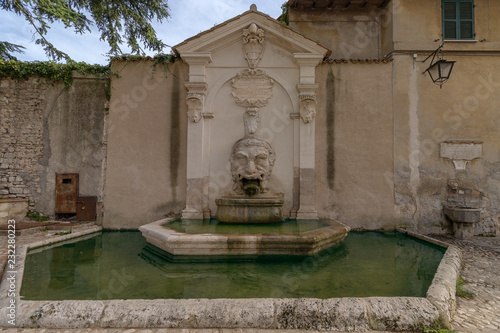 Old fountain  Fontana del Mascherone  on the wall of the thirteenth-century former church of Saints Simon and Jude in  Spoleto  Umbria  Italy