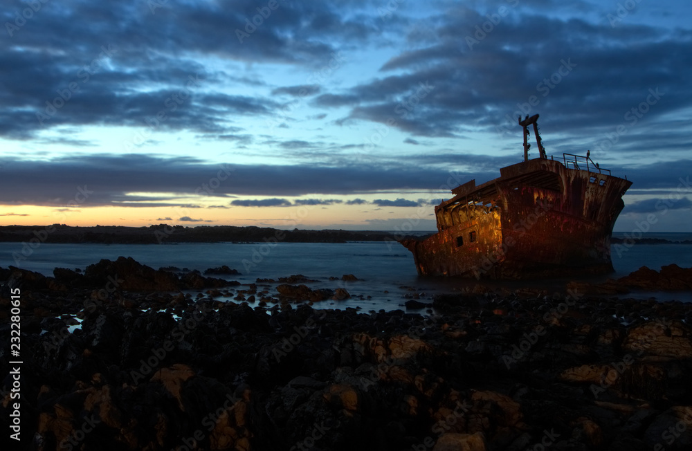 Old shipwreck on the rocks at sunrise.