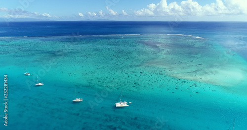 Boat in the Pacific Ocean under the blue sky. We can only see the Ocean and the blue lagoon all over the horizon - aerial view with a drone - travel and vacation concept © Fly_and_Dive