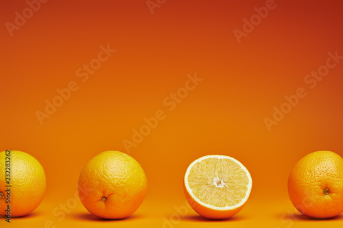 close-up view of fresh ripe whole and halved oranges on orange background
