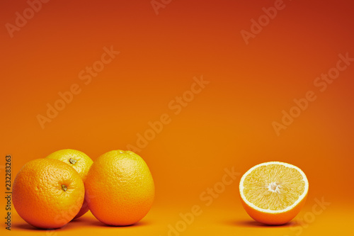 close-up view of whole and halved oranges on orange background