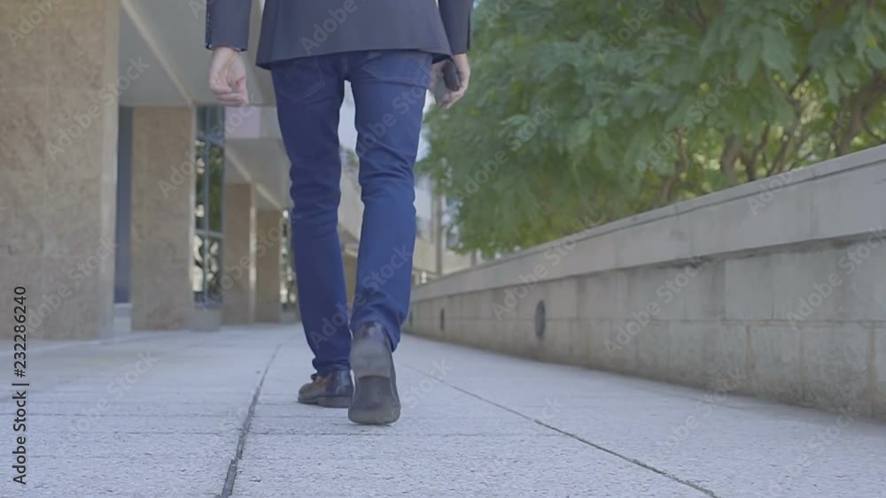 Cropped view of businessman walking with smartphone on street. Low section of manager going to office. Work concept Cropped view of businessman walking with smartphone on street. Low section of manager going to office. Work concept