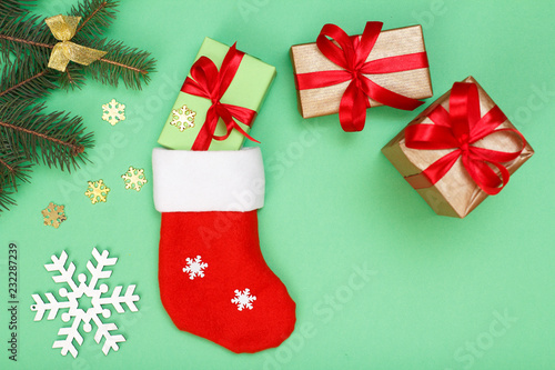 Santa's boot, gift boxes and fir tree branch on green background