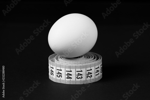 Chicken egg and centimeter on a black background. Close up