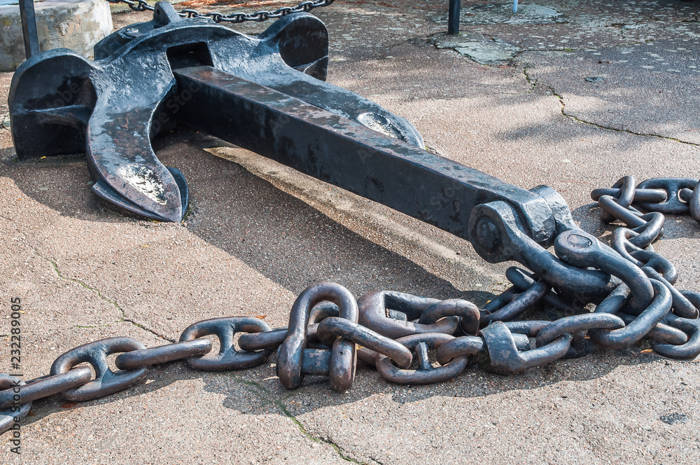 Heavy iron metal ship anchor with chain on gray asphalt. Side view. Stock  Photo