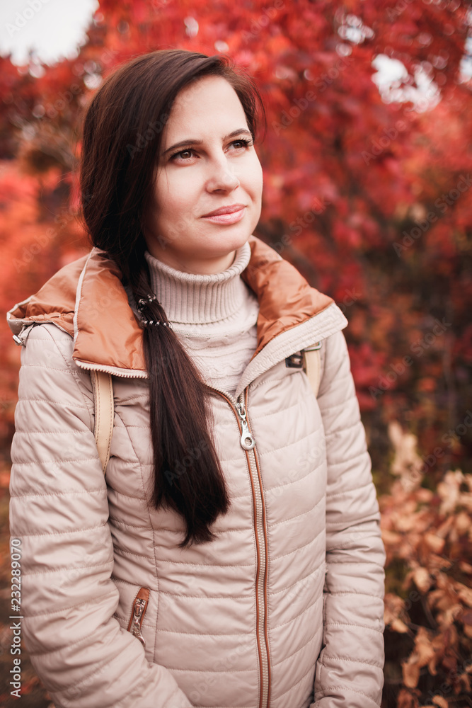 The girl one in the autumn park stands near a tree bush The girl one in the autumn park stands near a tree bush