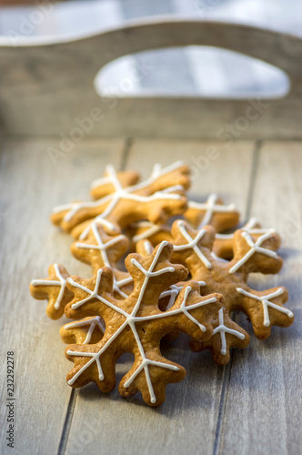 Painted traditional Christmas gingerbreads arranged on wooden tray in daylight, group of snowflakes, white sugar icing