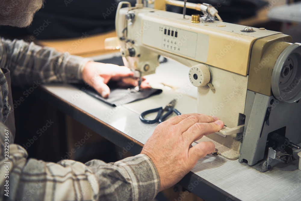 cropped image of male tailor working on sewing machine at studio