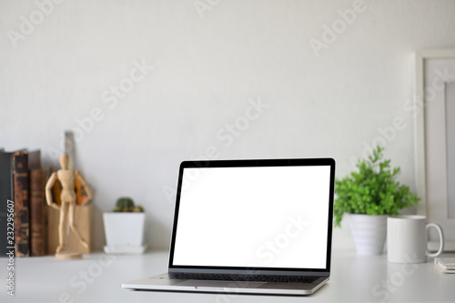 Workspace with blank white screen laptop on loft desk.