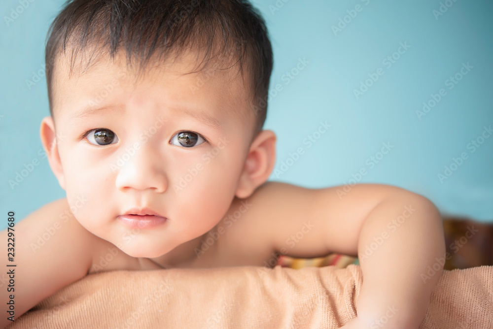 Solo cute Asian baby sitting in blanket smiling and suspect on face - obrazy, fototapety, plakaty 