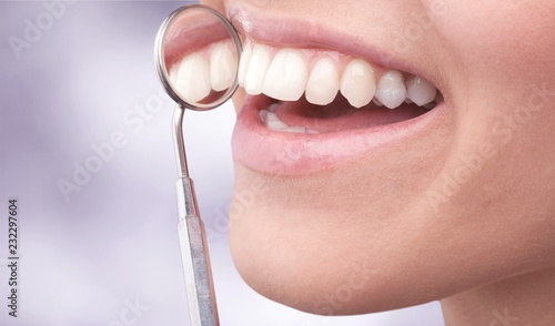 Woman teeth and a dentist mouth mirror on background