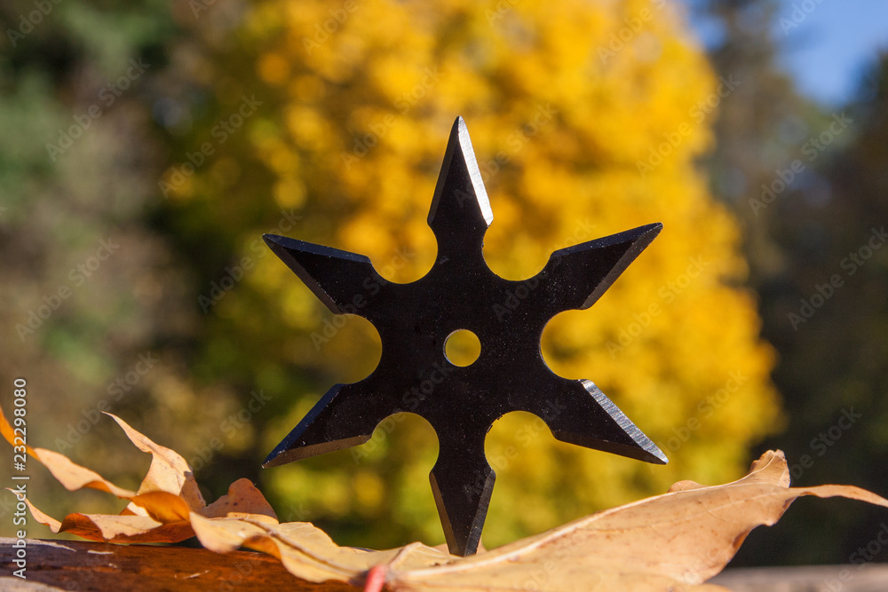 Shuriken (throwing star), traditional japanese ninja cold weapon stuck in wooden background Shuriken (throwing star), traditional japanese ninja cold weapon stuck in wooden background